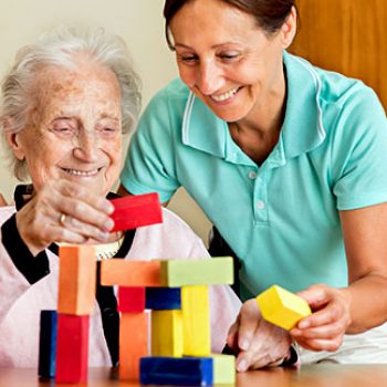Dementia and Occupational Therapy - Home caregiver and senior adult woman playing with blocks